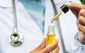 dr holding a container of cbd oil in a dropper